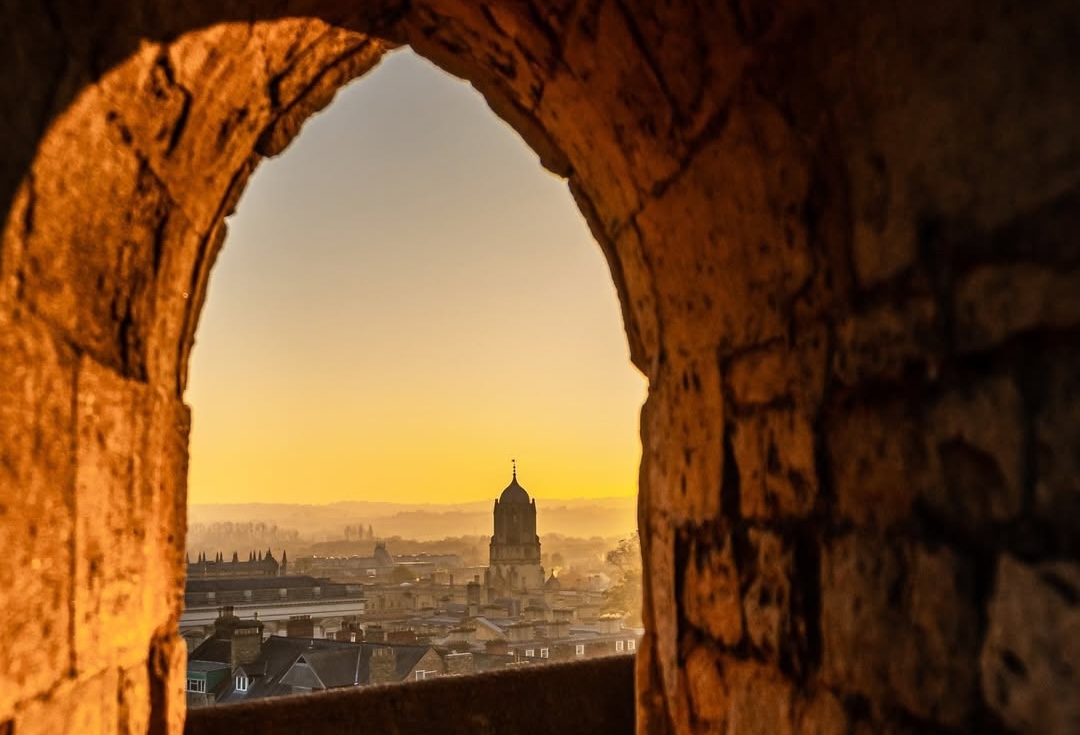 A sunset over Oxford's historic skyline showing the iconic 'dreaming spires' of the university buildings